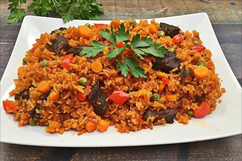 Jollof-Reis serviert mit Fleisch und Paprika